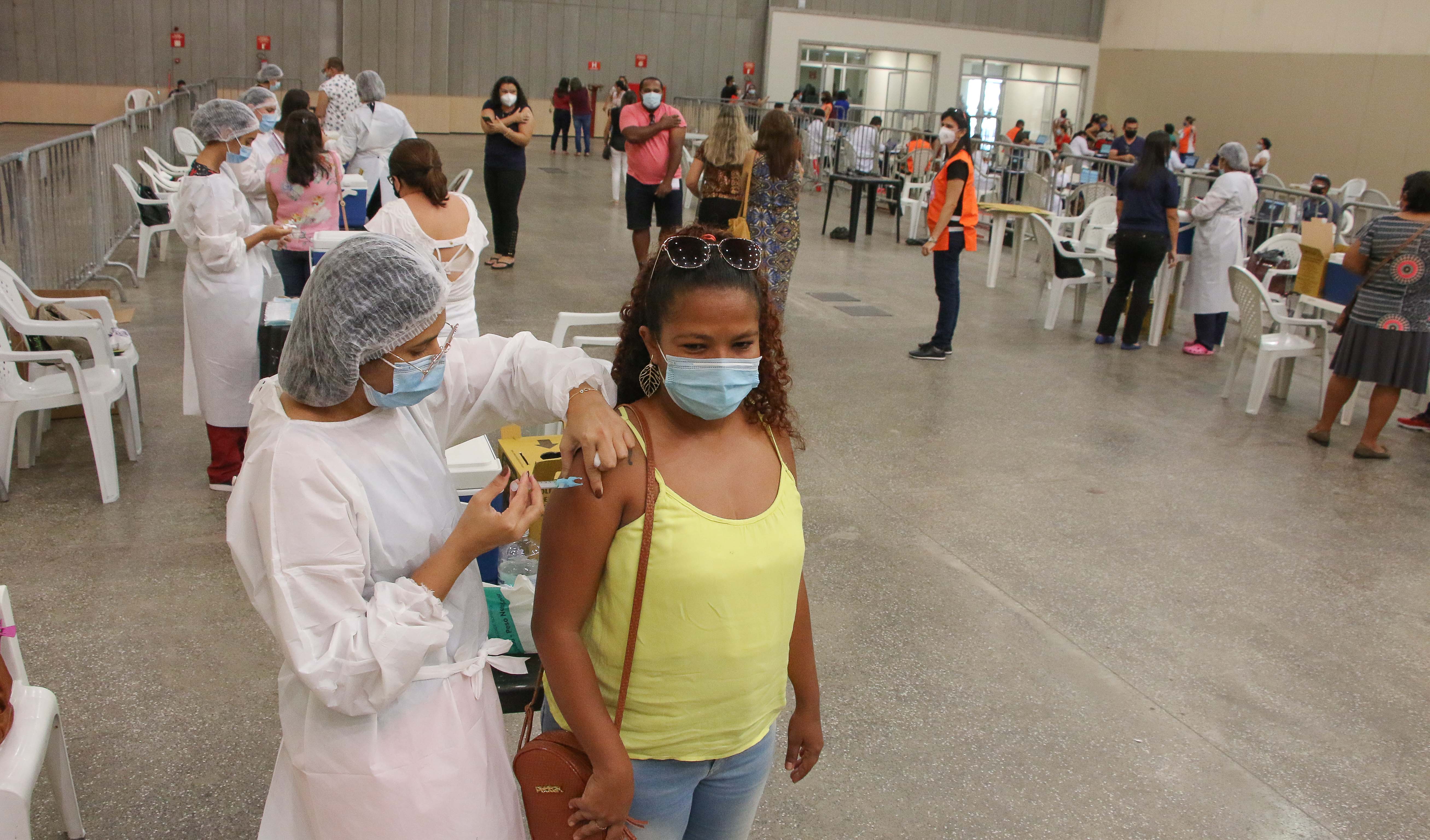 Foto aberta mostrando um grupo de pessoas sendo vacinado